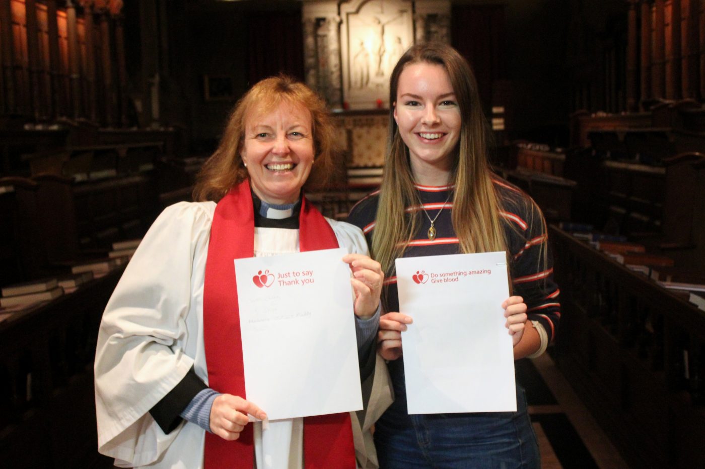 Chaplain and student holding blood donation sign-up sheets